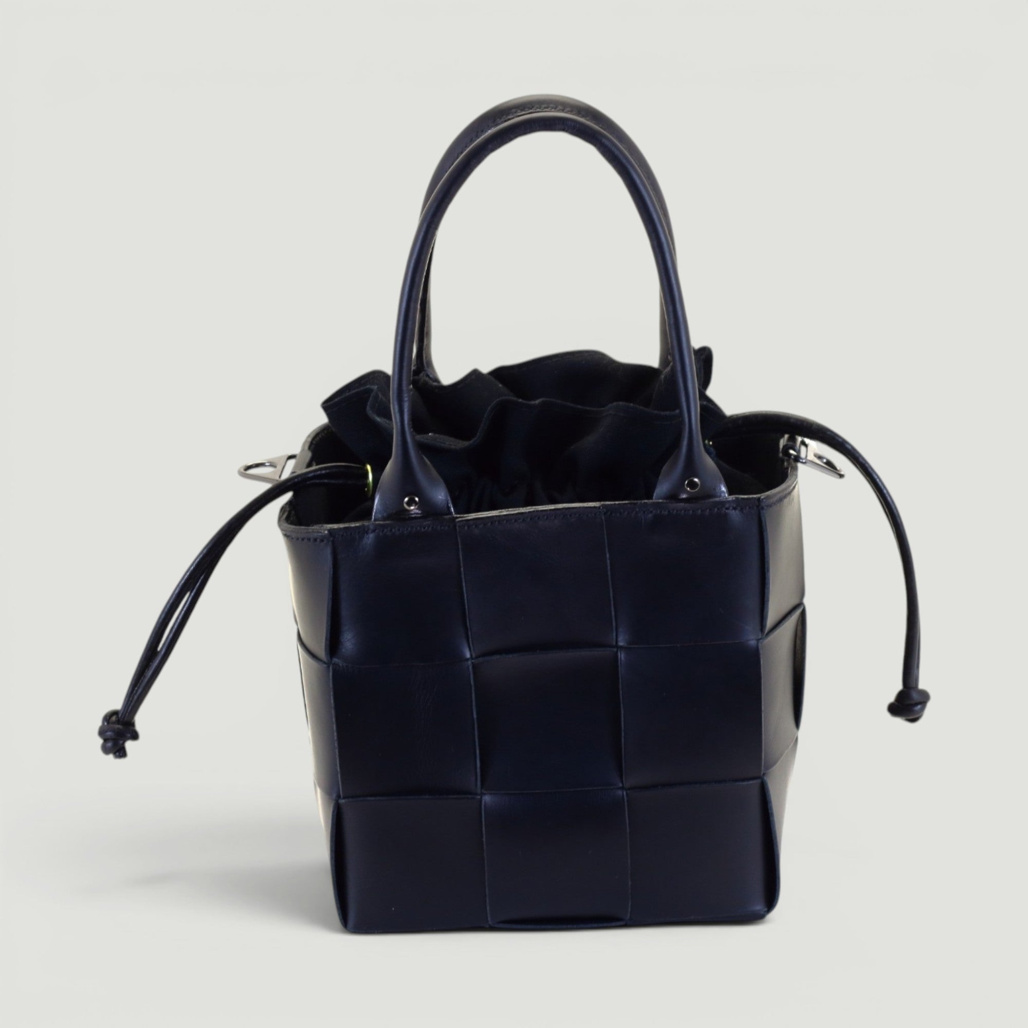 GJEN DESIGN navy blue woven leather bucket handbag with a structured grid pattern and secure drawstring closure.
