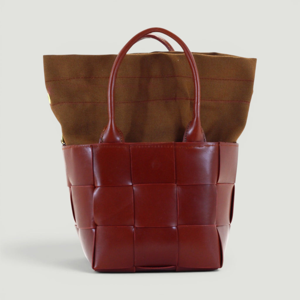 GJEN DESIGN mahogany woven leather bucket tote bag with a brown canvas insert and sturdy leather handles.