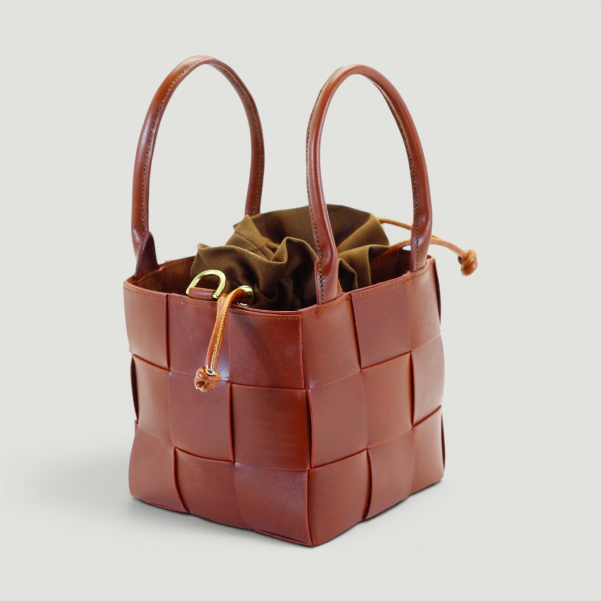 GJEN DESIGN mahogany woven leather bucket tote bag with a brown canvas drawstring insert and sturdy top handles.